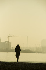 Woman standing alone looking at the town in the fog