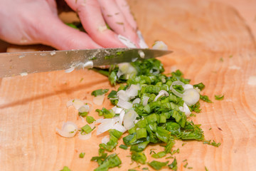 The girl cuts onions on a wooden board