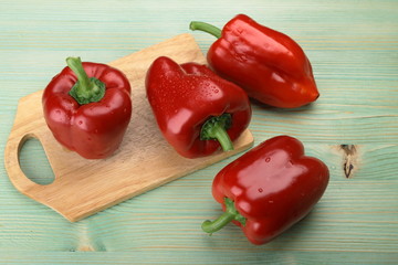 Red pepper on the green wooden background.