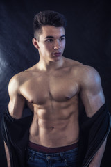 Fototapeta premium Handsome young muscular man shirtless wearing jeans, isolated on black background in studio shot