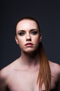 red head model with an edgy personality looking sexy in a dark studio with edgy lighting