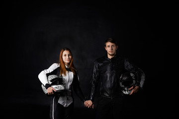 Portrait of biker man with girlfriend in motorcycle leather equipment and motorbike helmets hold...