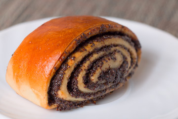 Roll with poppy seeds on a plate. Selective focus.