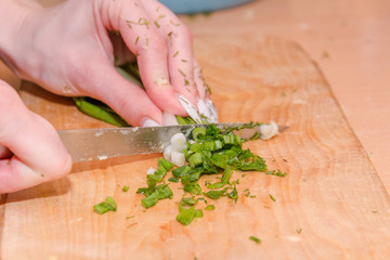 The girl cuts onions on a wooden board