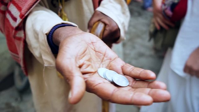 beggar asking alms in the form of coins stretching a dirty old hand with a trifle