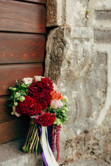 Wedding bridal bouquet of roses, celosia, Proteus against the backdrop of an old door. Wedding in Montenegro, Adriatic.