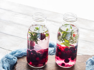 Detox infused water with berries and rosemary herb on wooden background