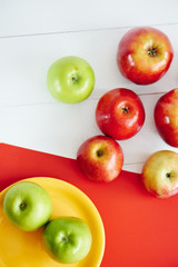 Top view of apples on a yellow plate and white wooden surface