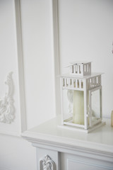 All white. White lantern with a candle standing on the mantelpiece white