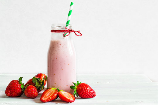 Strawberry smoothie or milkshake in a bottle with straw
