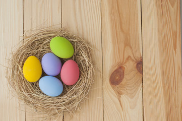 Easter Eggs in nest on wood background