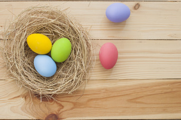 Easter eggs in nest on wood background