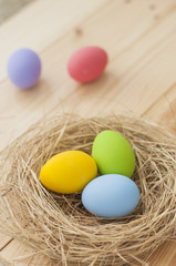 Easter eggs in nest on wood background