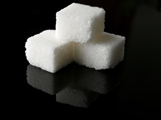 three sugar cubes over black background