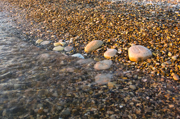 Fototapeta na wymiar sea pebble beach with multicoloured stones, waves with foam