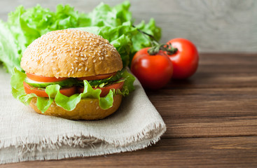 A sandwich with vegetables on a wooden background. Tomatoes and bread on the table.