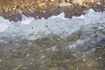 sea pebble beach with multicoloured stones, waves with foam