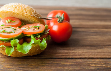 A sandwich with vegetables on a wooden background. Tomatoes and bread on the table.
