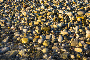 sea pebble beach with multicoloured stones, waves with foam