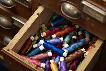 Fototapeta na wymiar Scraping full of beautiful colorful yarn rolls for sewing dresses for any occasion as a hobby or profession