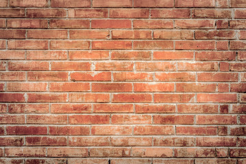 Old red brick wall with cracks and scratches. Horizontal wide brickwall background. Distressed wall with broken bricks texture. Vintage house facade.