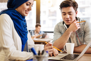 Cheerful students using laptop for studying