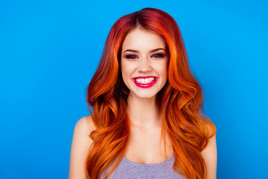 Close-up of attractive cute girl with long ginger fair hair with toothy beaming smile while standing on blue background