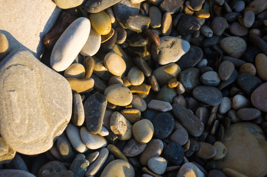 Fototapeta sea pebble beach with multicoloured stones, waves with foam