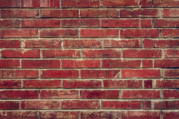 Old red brick wall with cracks and scratches. Horizontal wide brickwall background. Distressed wall with broken bricks texture. Vintage house facade.