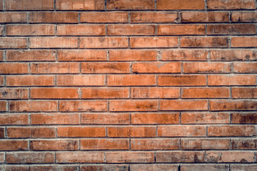 Old red brick wall with cracks and scratches. Horizontal wide brickwall background. Distressed wall with broken bricks texture. Vintage house facade.