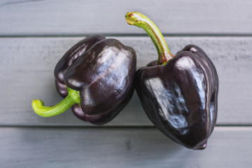  two black paprika's on a gray wooden board