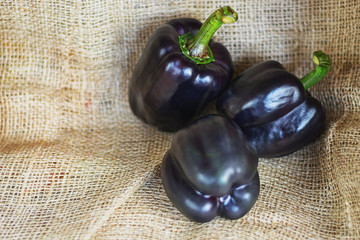 three black paprika's on a piece of jute