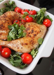 Baked chicken quarter with cherry tomatoes. Roast chicken quarter with the addition of cherry tomatoes. Selective focus