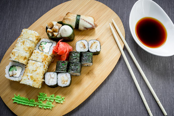 Japanese food - set of sushi rolls, sauce, wasabi and chopsticks on gray background. Top view. Flat lay