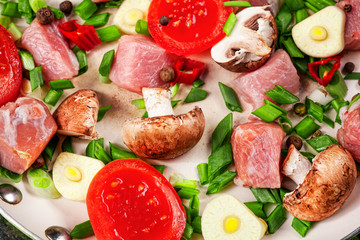 Raw meat in dish and frying pan, spices, knife on wooden table, vegetables, top view