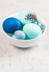Plate with painted blue eggs on aged wooden table desktop