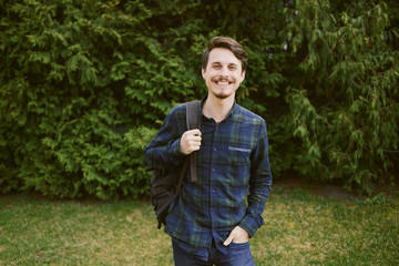 Young guy with a backpack in the park, green background