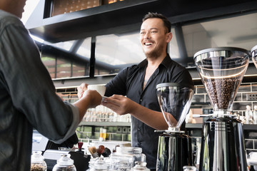 Friendly bartender serving espresso coffee to a customer in a modern coffee shop