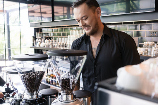 Happy young man preparing espresso while working as barista in a modern coffee shop
