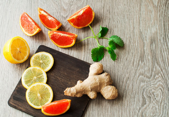 Ginger and lemon, spices and ingredients for drinks. Red oranges, citrus fruits on a wooden background.