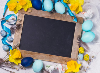 Easter frame with painted blue eggs and flowers and empty chalkboard with copy space