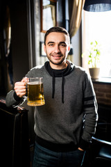 single man in a pub or bar holding mug the beer high in the air for cheers
