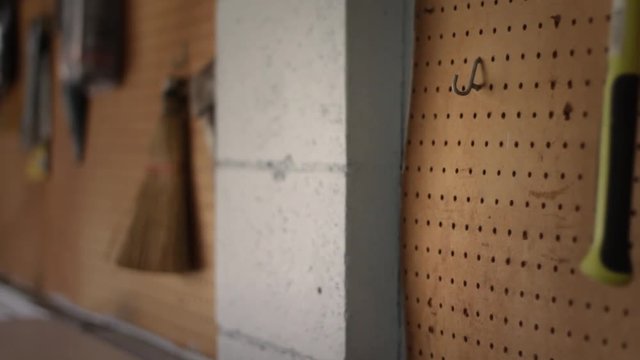 Homeowner grabs a crowbar from a toolroom rack on wall