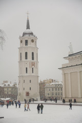 Obraz premium Vilnius, Lithuania - December 11, 2016: capital city square with snow falling on cathedral church tower Europe Baltic countries