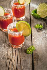 Mexican traditional alcohol drink. Sangrita, with tequila, tomato juice, hot spices, chili and lime.Analogous bloody mary. On rustic wooden table, copy space