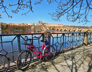Fototapeta premium Prague Castle with famous Charles Bridgea and with pink bike in the foreground in Czech Republic