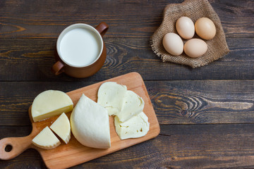 cheese with milk and some eggs on a wooden table. Top view