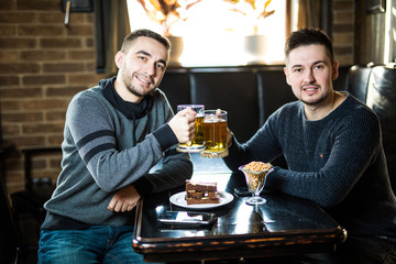 Two handsome friends in a pub with glasses of beer. Friends time.
