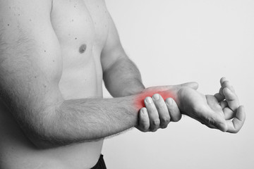 Young man holding his hand because of pain or checking his pulse or heartbeat