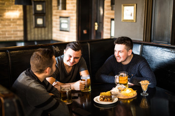 Meeting at the pub. Three happy friends drinking beer at the traditional pub